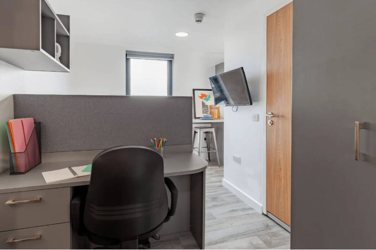 A modern office space with a desk, chair, and cubicle partitions.
