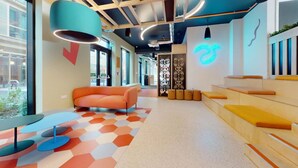 A modern interior with a curved orange sofa, a geometric patterned rug, and a neon sign on the wall. - For Students Only - Signal Place - Campus Accommodation (Nottingham)