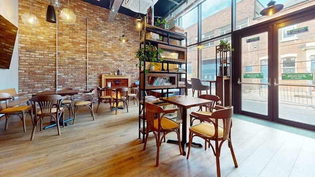 A restaurant interior with brick walls, wooden tables, and chairs. - For Students Only - Signal Place - Campus Accommodation (Nottingham)