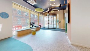 A modern interior with a round glass door, a bench, and a small table. - For Students Only - Signal Place - Campus Accommodation (Nottingham)