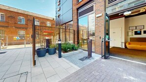 A modern building entrance with a glass door, a metal gate, and potted plants. - For Students Only - Signal Place - Campus Accommodation (Nottingham)