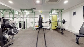 A gym with weightlifting equipment, a punching bag, and a bench. - For Students Only - Signal Place - Campus Accommodation (Nottingham)