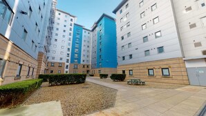 A courtyard with a gravel path, benches, and low-rise buildings with multiple windows. - Opal Court (Leicester)
