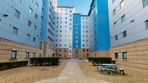 A modern apartment complex with a central courtyard, multiple floors, and a mix of blue and beige exterior walls. - Opal Court (Leicester)