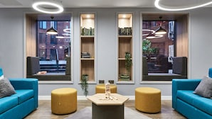Een moderne zithoek met blauwe banken, een centrale salontafel en ingebouwde boekenkasten.