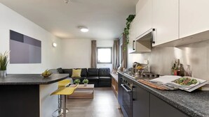 Une cuisine moderne avec un coin repas, comprenant un canapé noir, des chaises jaunes et un îlot central doté d’un évier et d’une cuisinière.