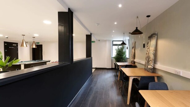 L’intérieur d’un restaurant moderne, avec un long comptoir, des tables en bois et des chaises noires.