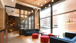 A modern interior with a sofa, ottomans, and a coffee table. - For Student Only Liv Student Sheffield - Campus Accommodation (Sheffield)