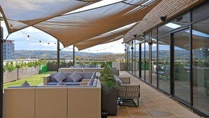 A rooftop terrace with outdoor seating, a large windowed wall, and a view of the cityscape. - For Student Only Liv Student Sheffield - Campus Accommodation (Sheffield)