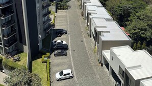 A modern apartment building with multiple floors, a parking area, and a view of a residential area with red-roofed houses. - Modern Apartment with Volcano View 901 Santa Tecla (Santa Tecla)
