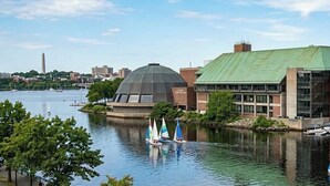 A waterfront building with a green roof, sailboats on the water, and a city skyline in the background. - The Niche: A cozy perfection!
Newly Renovated Family Friendly! Near Boston (Medford)