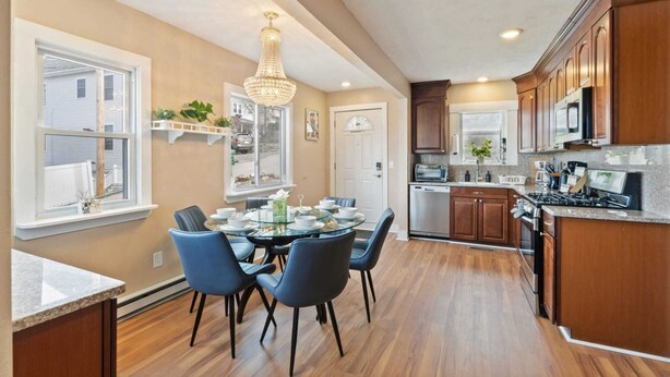A modern kitchen with wooden cabinets, a stainless steel stove, and a dining area with a glass table and chairs. - The Niche: A cozy perfection!
Newly Renovated Family Friendly! Near Boston (Medford)