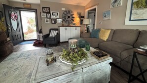 A cozy living room with a wooden coffee table, a sofa, and a clock on the wall.
