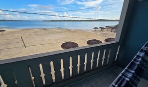 Un balcón con vista a una playa y un lago tranquilo.