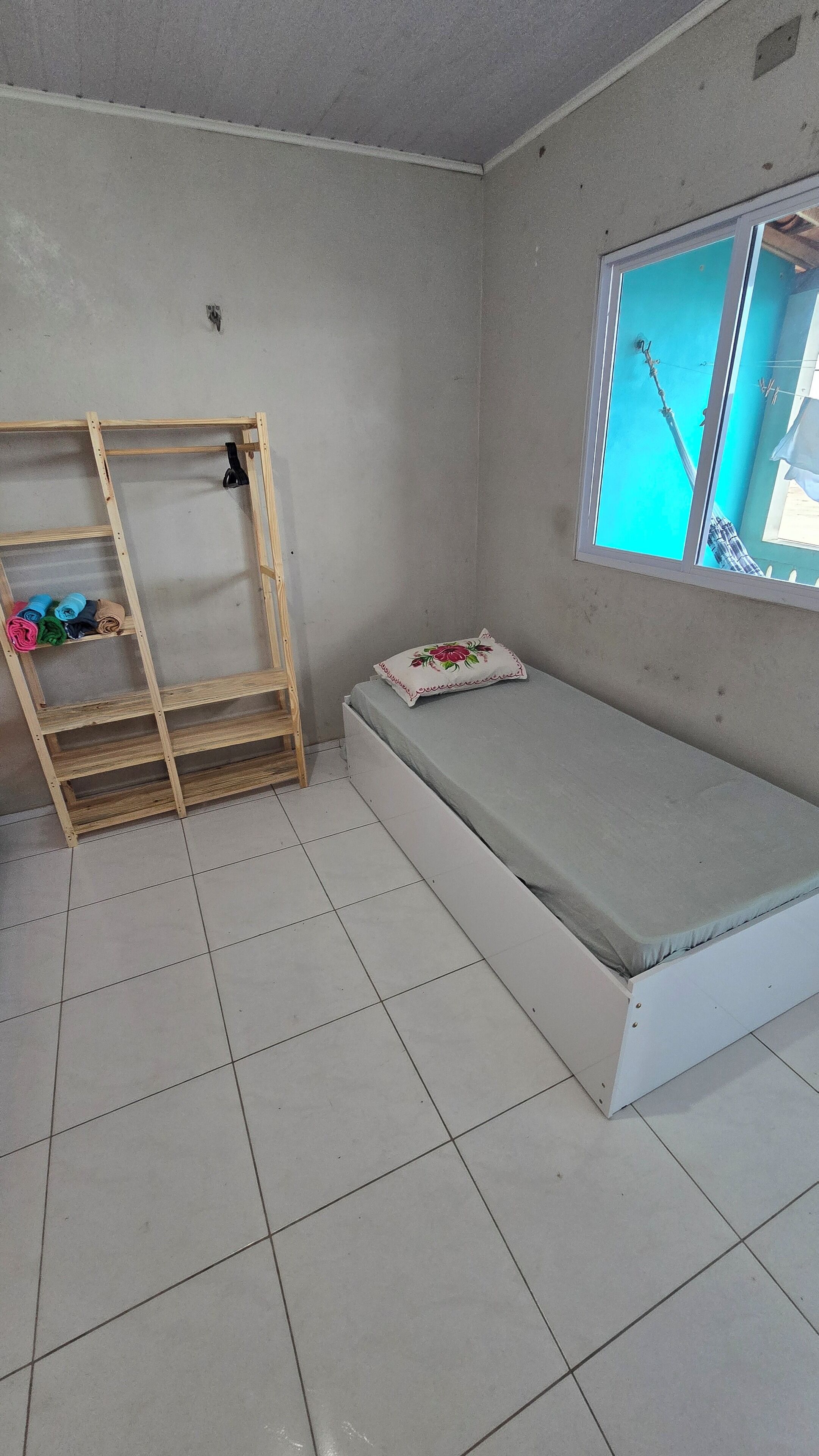 A room with a bed, a wooden ladder, and a window with a view.