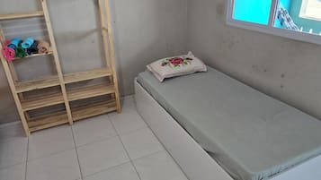A room with a bed, a wooden ladder, and a window with a view.