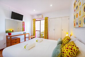 A hotel room with a bed, a desk, a chair, a TV, and a wardrobe.