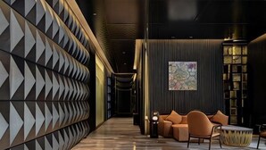 A modern interior with a geometric wall design, a seating area with a sofa and armchairs, and a bookshelf. - Empathy Hotel (Guangzhou East Railway Station Tianhe Sports Center) (Guangzhou)