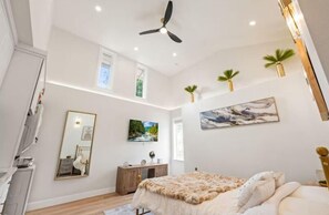 Ein Schlafzimmer mit Bett, Kommode, Spiegel, Deckenventilator und einem Bild an der Wand.