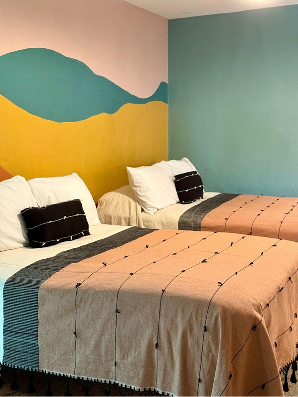 Una habitación de hotel con dos camas, cada una con un estilo diferente de ropa de cama y almohadas.