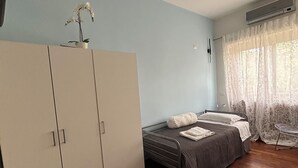 A bedroom with a bed, wardrobe, and an air conditioning unit.