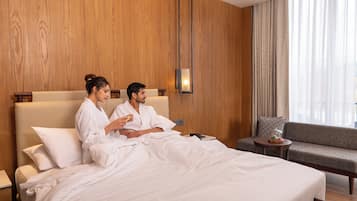 A hotel room with a large bed, a sofa, a small table, and a wall-mounted lamp.