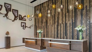 Een receptiezone met een houten receptiebalie, kunstwerken aan de muur en hangende pendellampen.