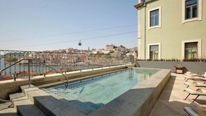 Uma piscina no terraço com vista clara para o horizonte urbano, incluindo um teleférico e edifícios.