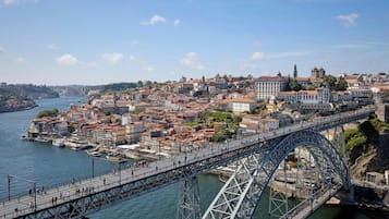 Uma grande ponte de aço que atravessa um rio, ligando duas áreas urbanas densamente povoadas com edifícios históricos.