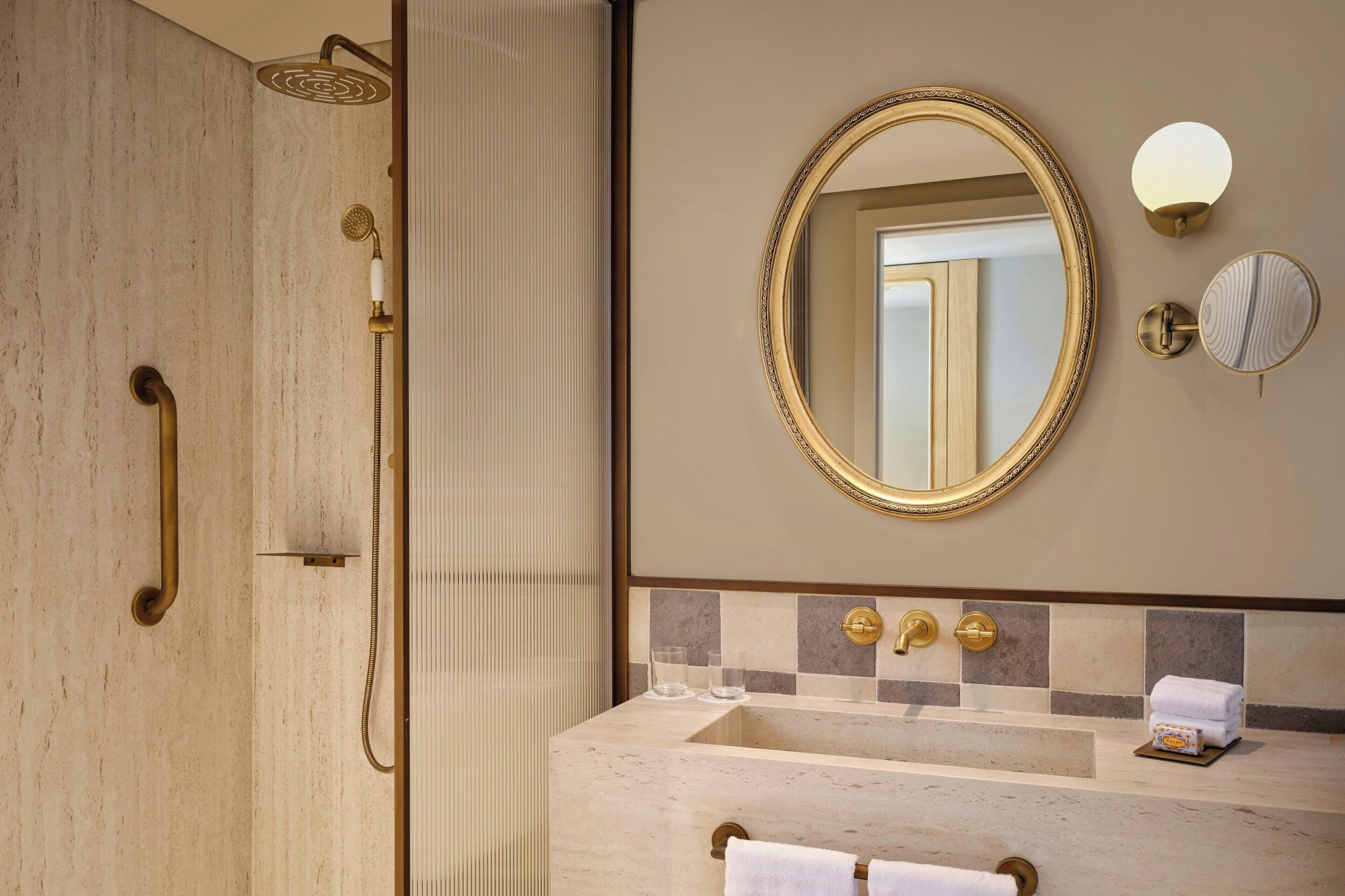 A bathroom with a shower, a sink, a mirror, and a towel rack.
