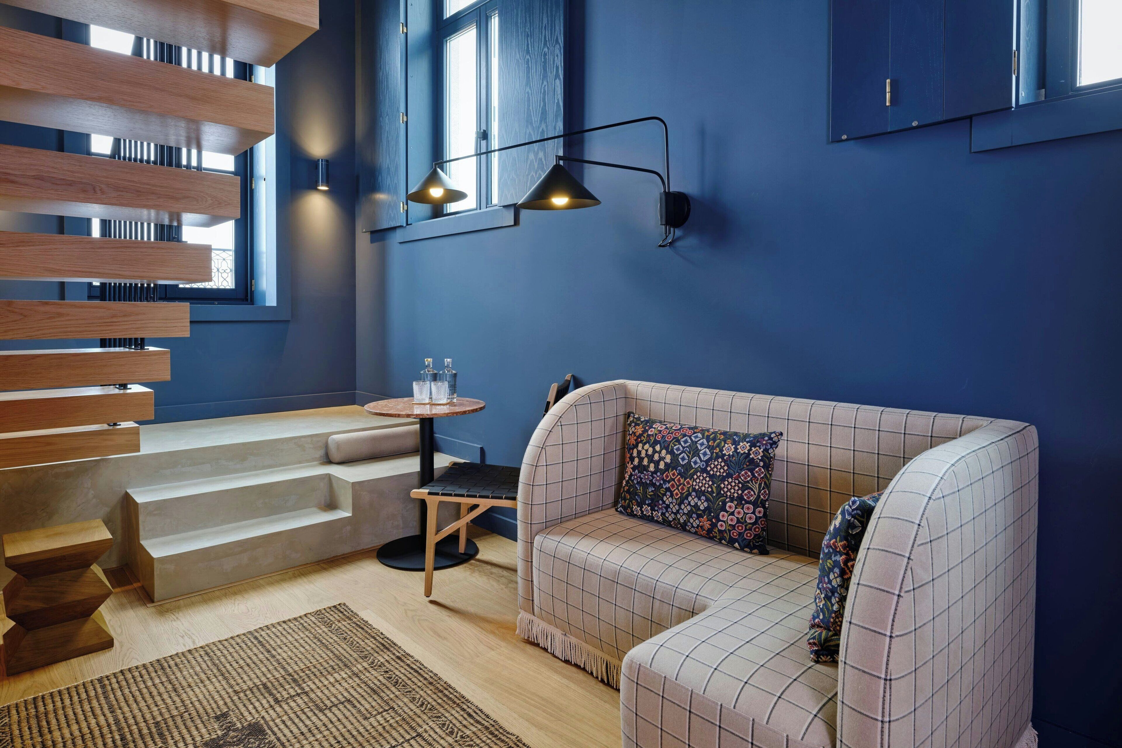 Un salon moderne avec un canapé à carreaux, un escalier en bois et une petite table ronde.