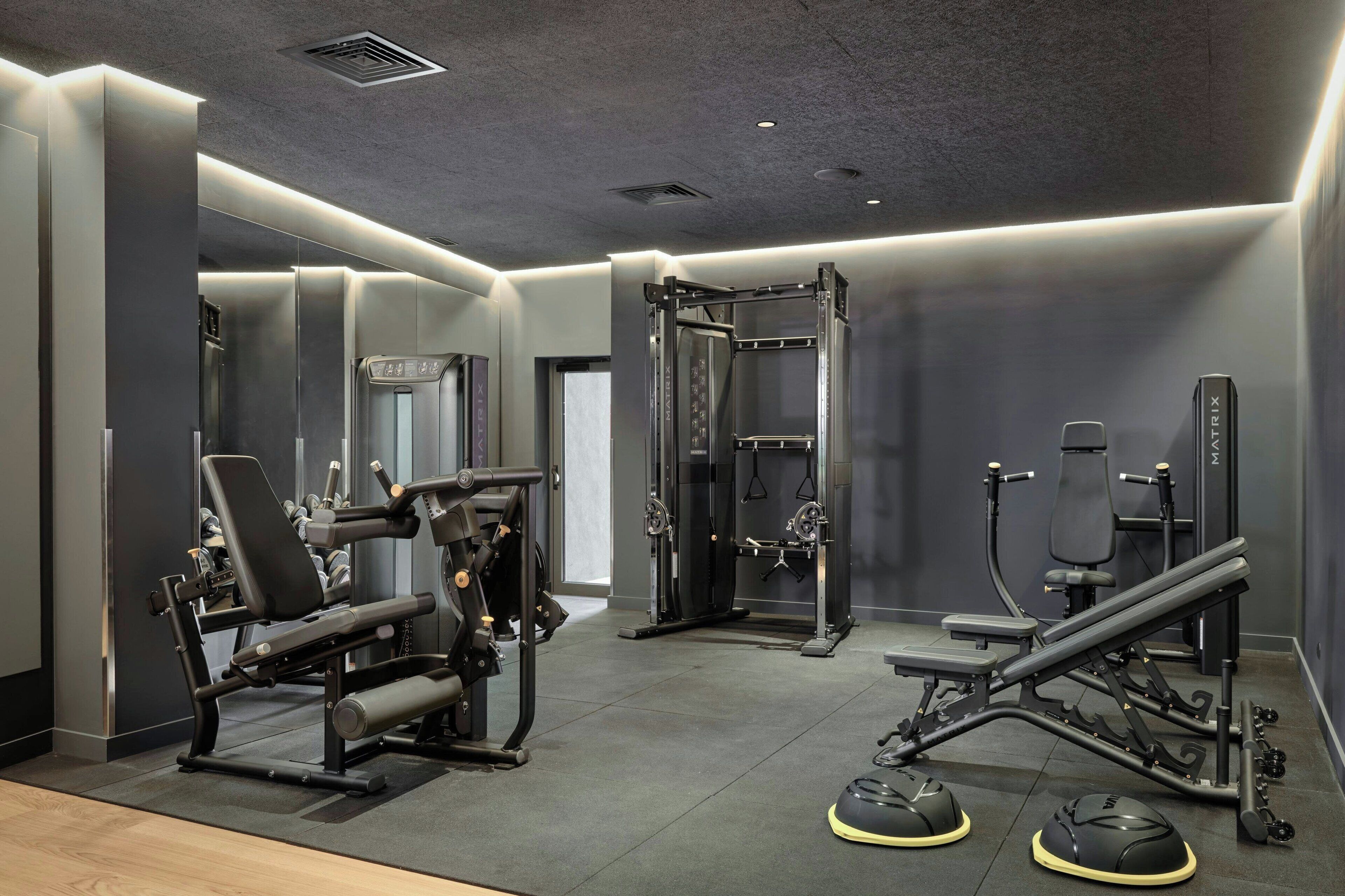 A modern gym with various exercise equipment, including a bench press, squat rack, and weight machines.