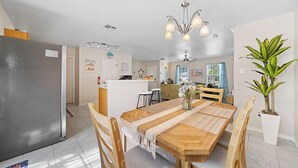 Eine moderne Küche mit einer zentralen Kochinsel, einem Holztisch mit Stühlen und einem Blumentopf.