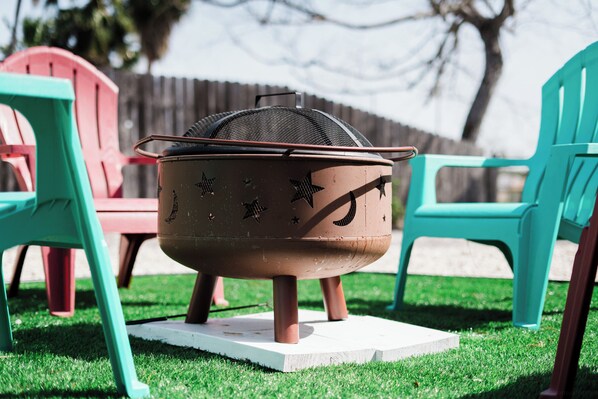 A portable cooking pot with a mesh lid, placed on a white base outdoors.