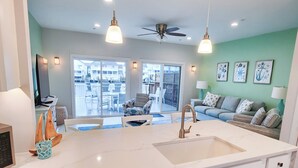 Una cocina moderna con una isla central, lavavajillas de acero inoxidable y armarios blancos.