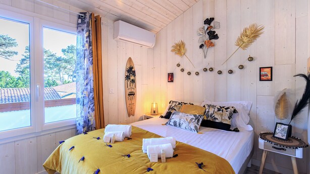 A hotel room with a bed, a window, and a wall decorated with various items. - Maison des Bonheurs Océaniques - Welkeys (Capbreton)