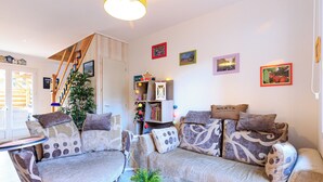 A cozy living room with a sofa set, a glass coffee table, and a staircase leading to another level. - Maison des Bonheurs Océaniques - Welkeys (Capbreton)
