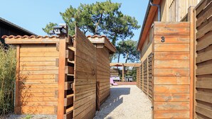 A wooden building with a gravel path leading to a covered area. - Maison des Bonheurs Océaniques - Welkeys (Capbreton)