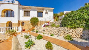 Un edificio blanco con un muro de piedra, una escalera de piedra y un camino de grava.