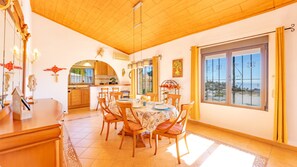 Zona pranzo con un tavolo rotondo, sedie e vista all'esterno tramite un'ampia finestra.