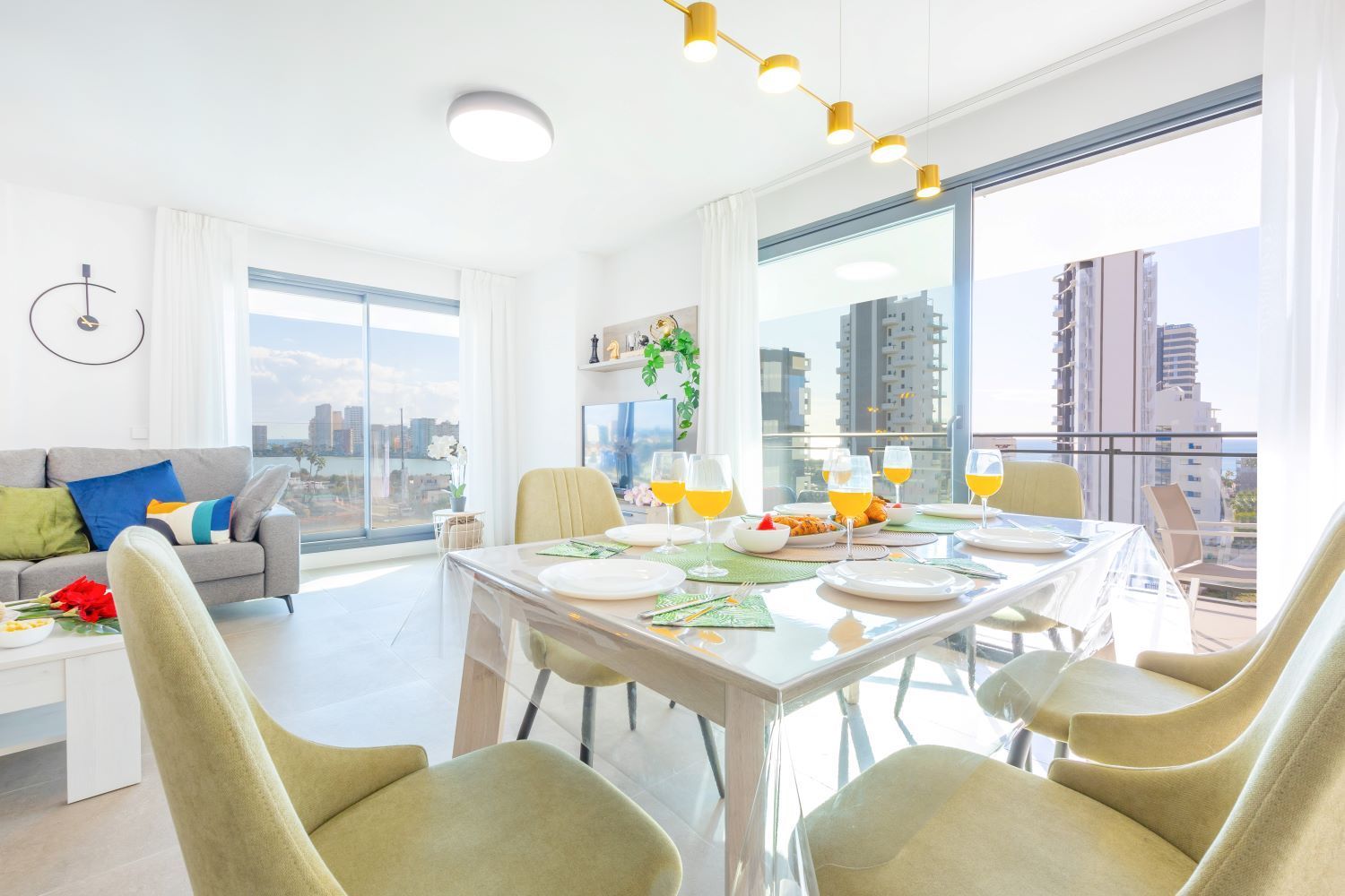 Un soggiorno moderno con zona pranzo, ampie finestre e vista sulla città.