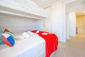Een hotelkamer met een bed, een rode deken, een kussen, een glas sinaasappelsap en een bord met eten.