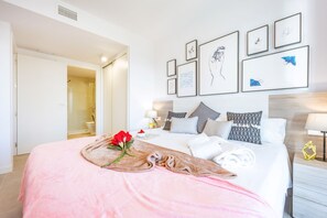 A hotel room with a bed, a bedside table, a lamp, and a wall with framed artwork.