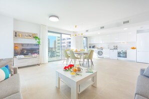 A modern apartment with a dining area, kitchen, and a large window overlooking a cityscape.
