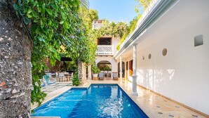 A swimming pool with a stone wall and a white building in the background. - Casa Palos - Old City - Luxury (Cartagena)