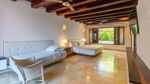 A bedroom with a large bed, a smaller bed, a chair, and a ceiling fan. - Casa Palos - Old City - Luxury (Cartagena)