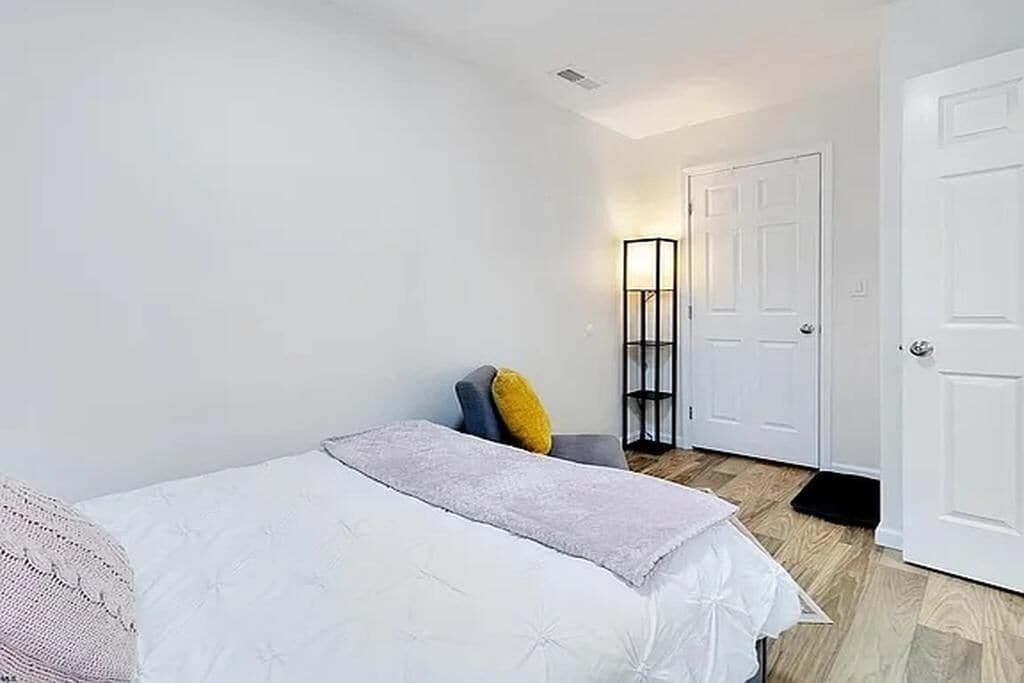 Una camera da letto con un letto, una sedia, un comodino e una porta.