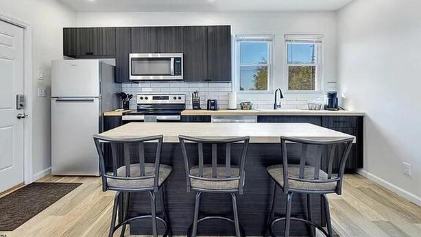 Een moderne keuken met een centraal eiland, barkrukken en een raam voor natuurlijk licht.