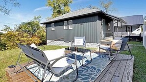 Een terras met tuinmeubilair, een kleine schuur en een huis op de achtergrond.