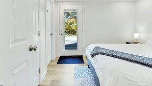 Een slaapkamer met een bed, een deur naar een balkon en een nachtkastje met een lamp.